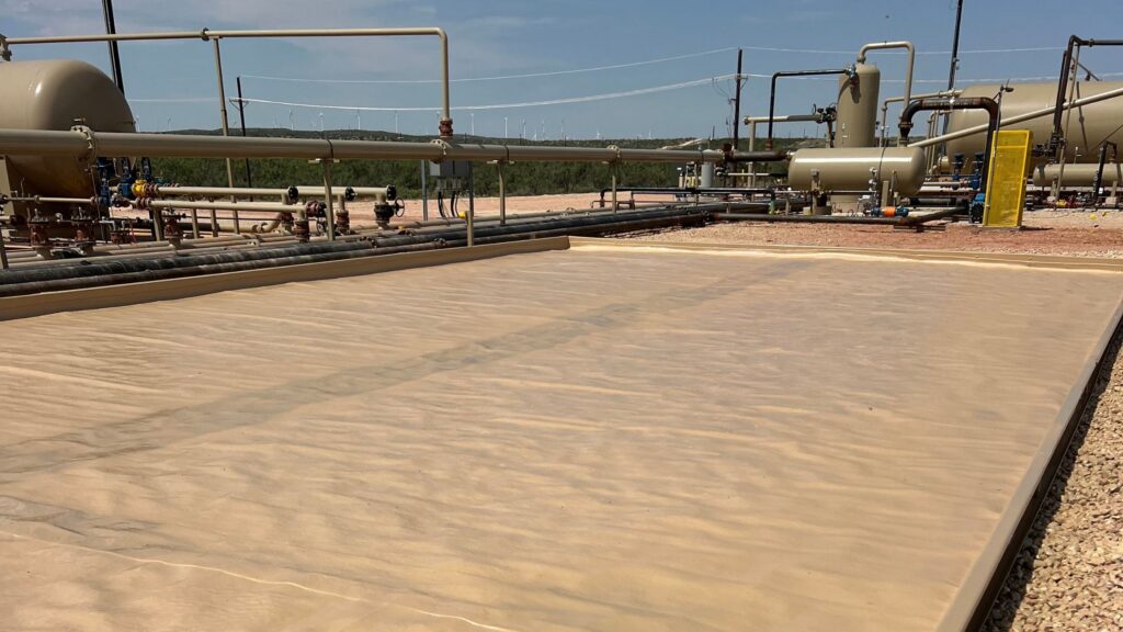 AssetGuard secondary containment solutions: tan GroundGuard liner at an oil and gas tank battery